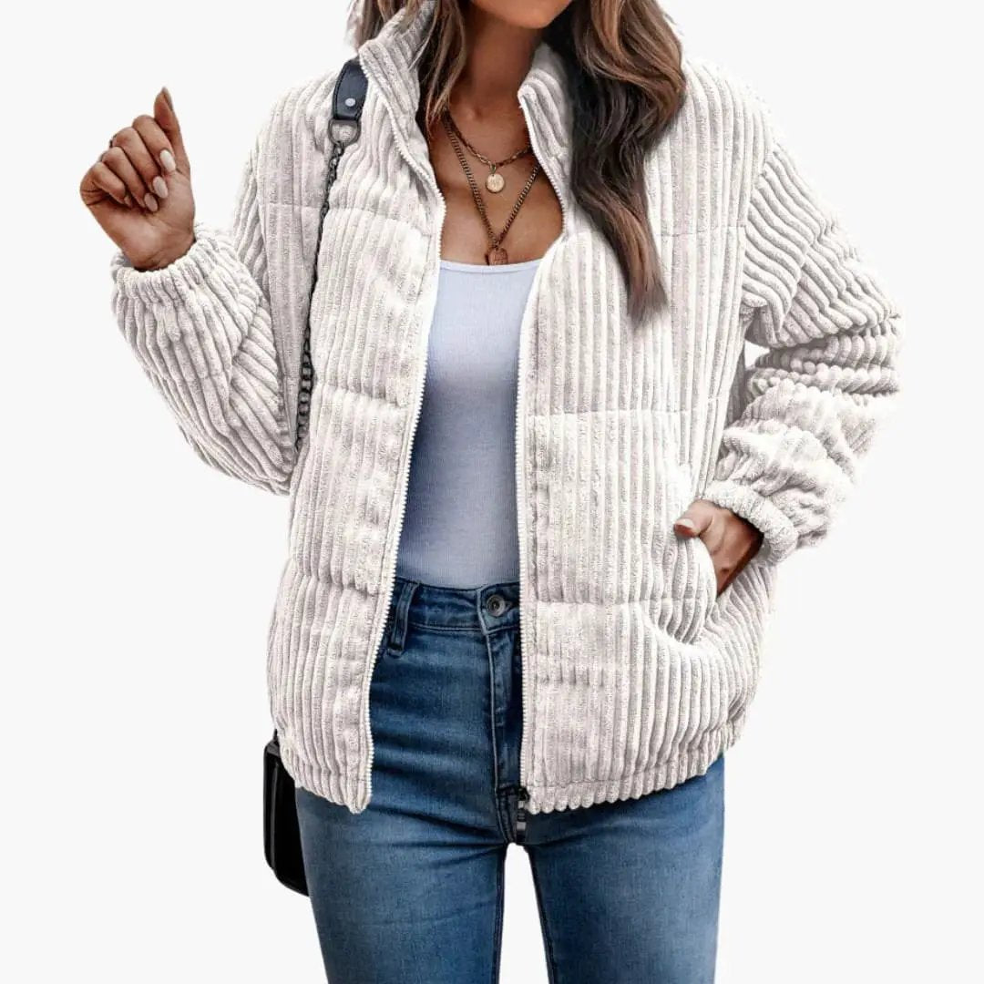 Women's beige ribbed jacket with front zipper, worn over a light blue top.