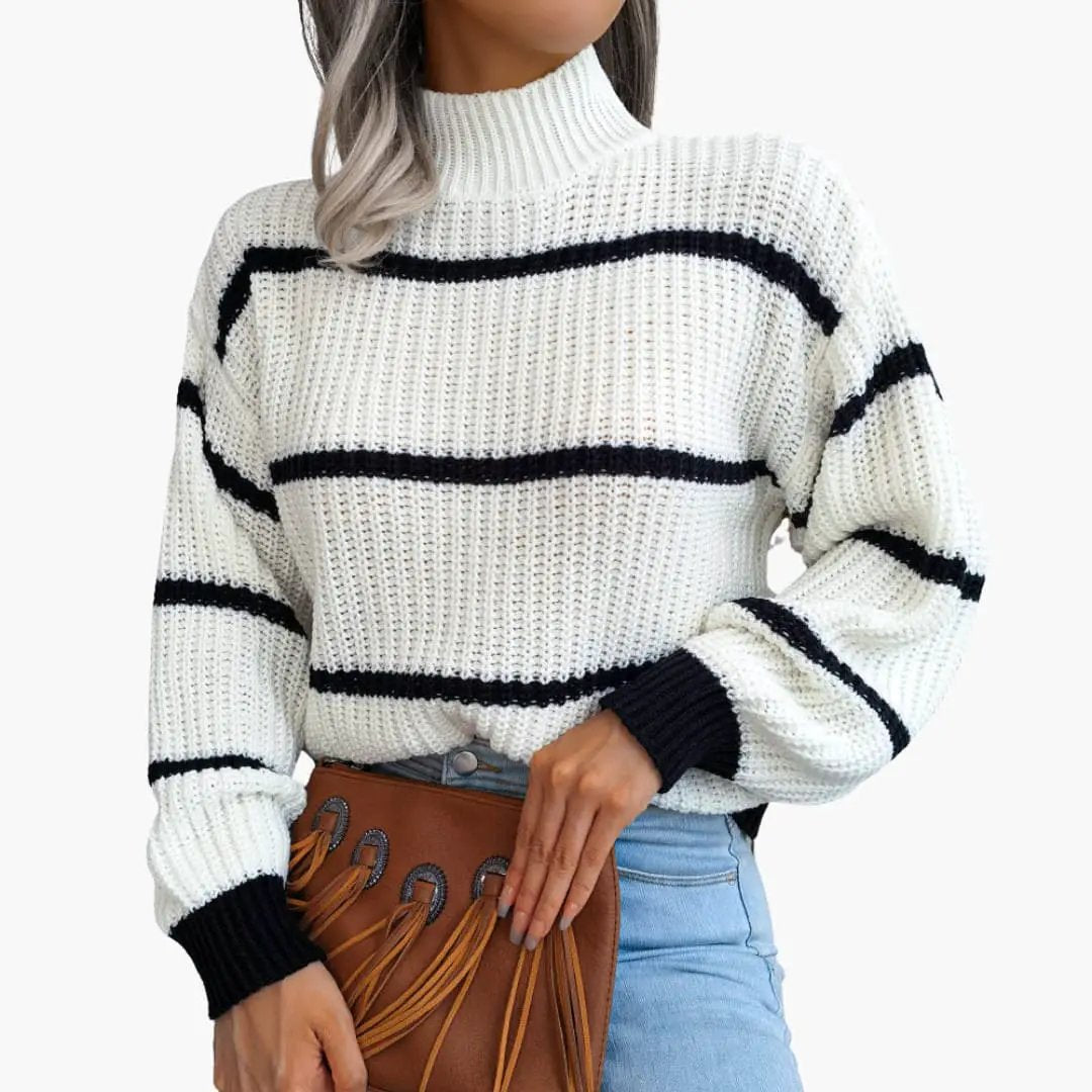 Women's knit sweater by Wilfred Smith with white chunky knit and black stripes, high collar, and brown fringed bag