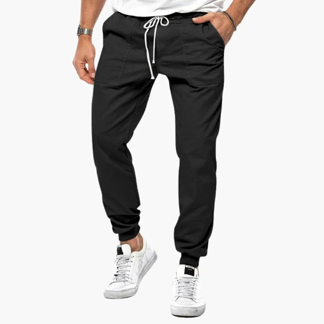 Men's jogging pants with elastic waistband in black, white drawstring, front pockets, and cuffed ankles.