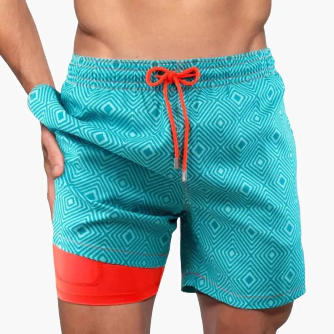 Men’s turquoise geometric boardshorts with orange drawstring and contrasting orange leg panel.