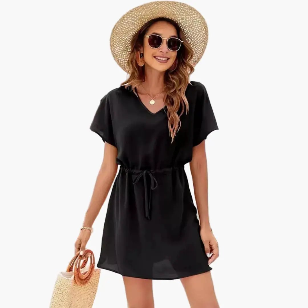 Women's black beach dress with V-neck and drawstring waist, styled with straw hat and woven tote.