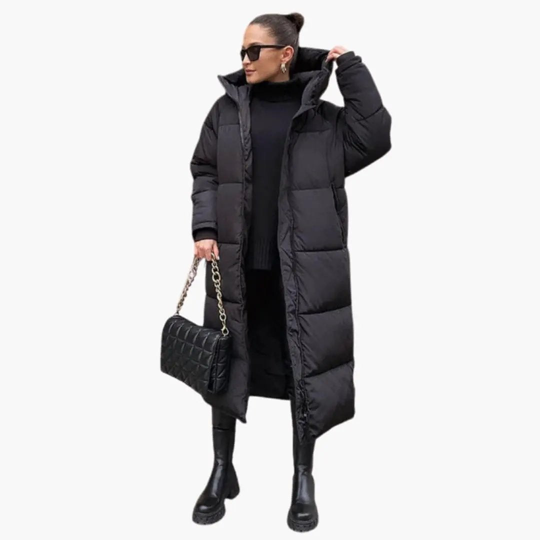 Women’s long quilted puffer jacket with high collar in black, Wilfred Smith; shown with a black quilted bag.