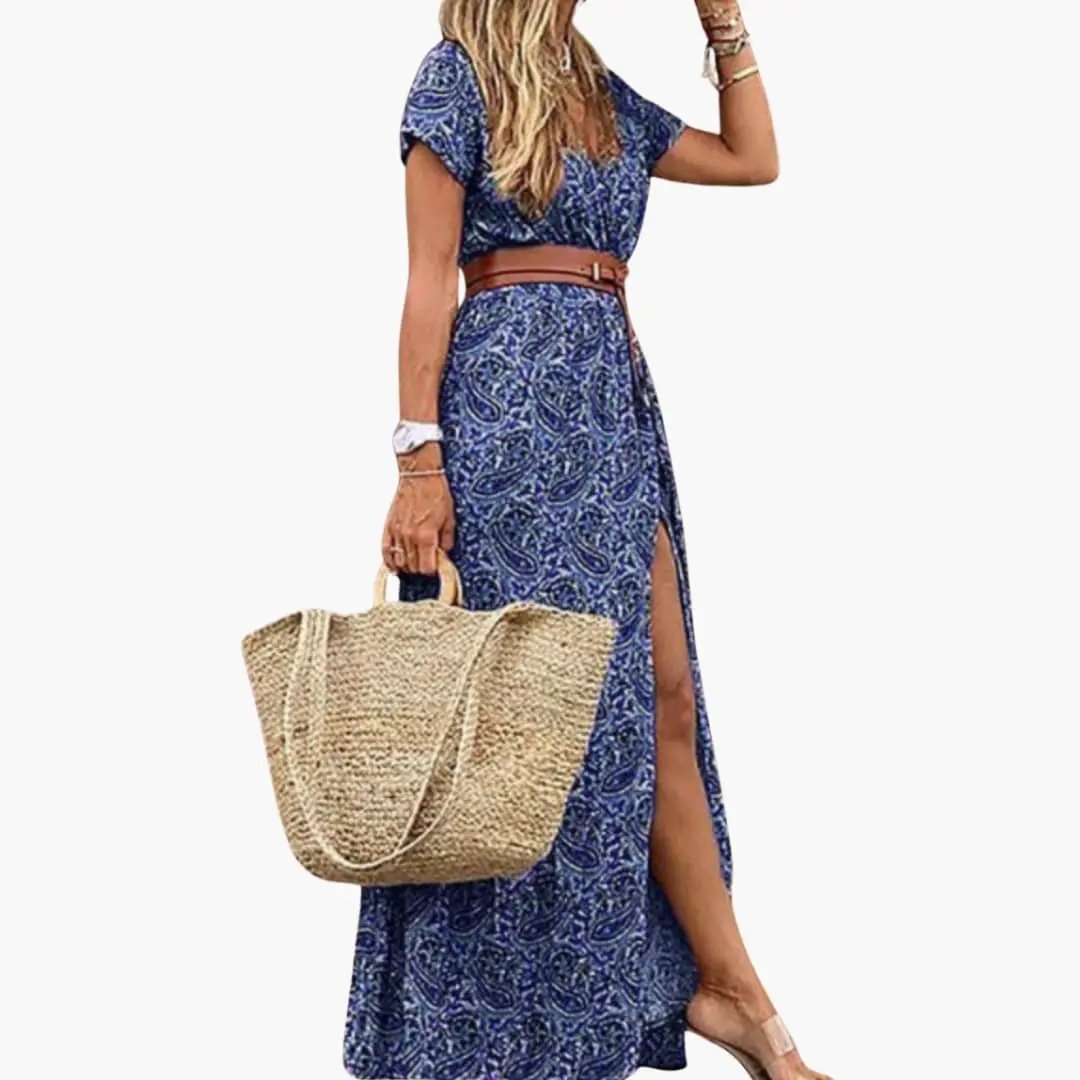 Women’s blue paisley maxi dress with belt, short sleeves and slit, paired with a straw tote.