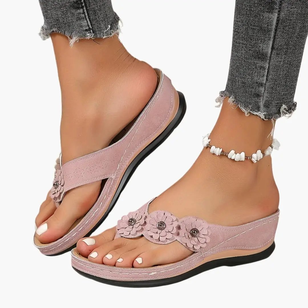 Women's orthopedic pink slip-on sandals with cushioned insole and decorative floral appliqué straps on a low black sole