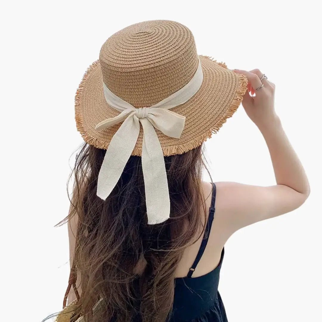 Women's sun hat by Wilfred Smith, with wide beige straw brim and white bow at back.