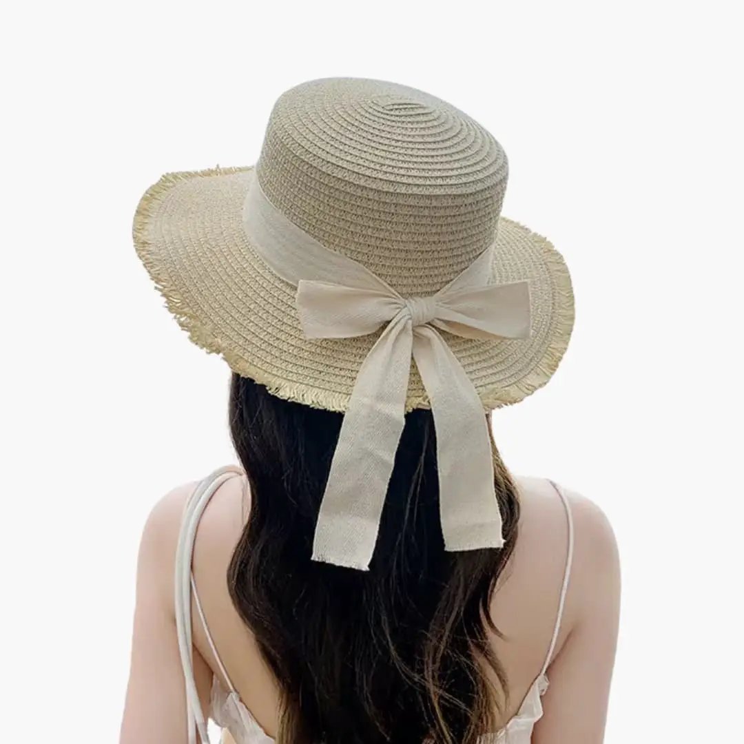 Women's sun hat by Wilfred Smith with a wide straw brim and beige ribbon bow at the back.