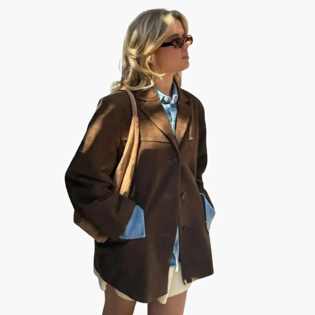 Women's brown oversized blazer with button closure and side pockets on model wearing a denim shirt underneath