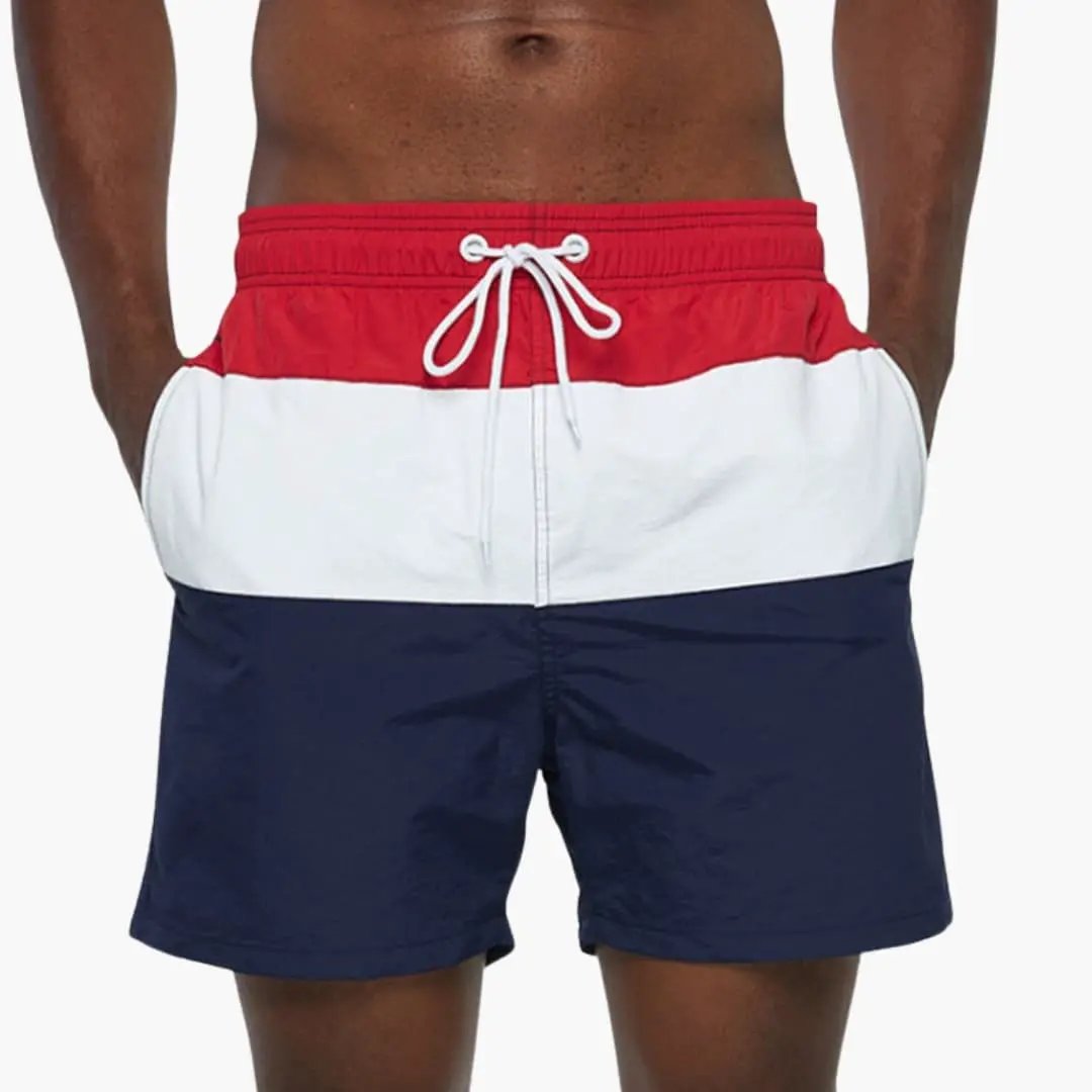 Men’s striped boardshorts with red, white, and navy panels and a white drawstring waist