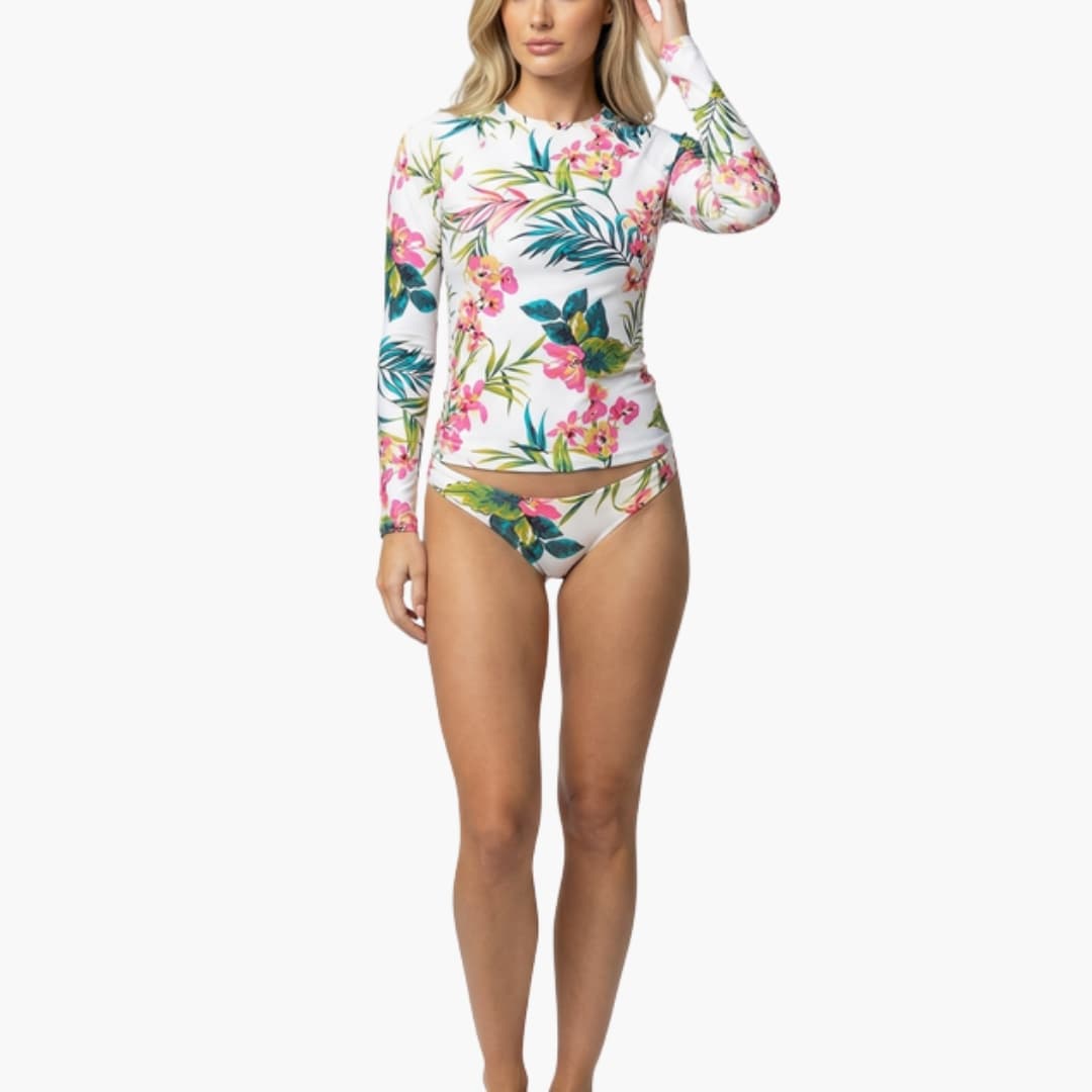 Women's floral long-sleeve rash guard bikini set with front zip on white base, tropical pink, green and blue flowers.
