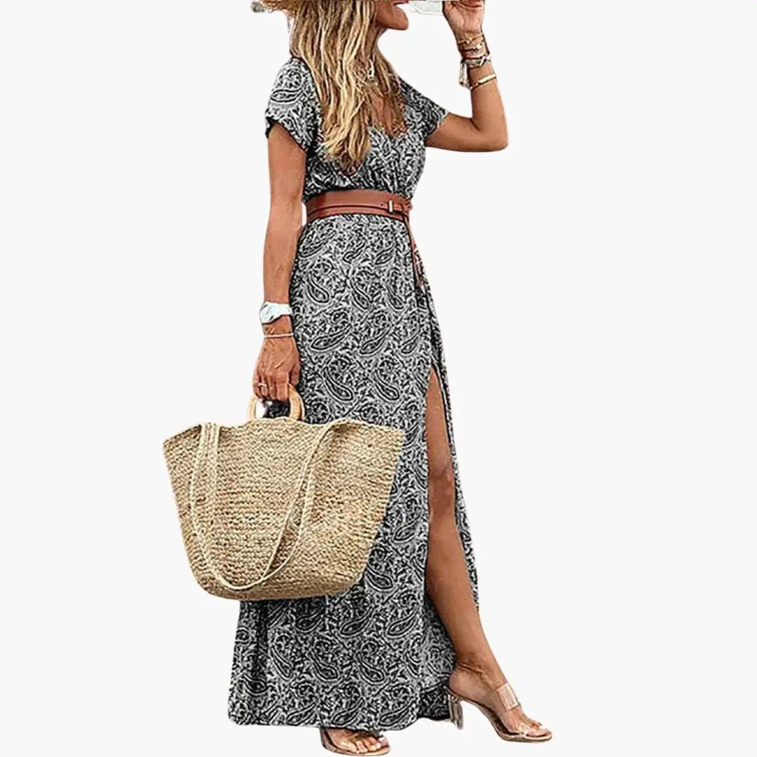 Women's maxi dress with brown belt in black-and-white paisley print, short sleeves, side slit; straw tote