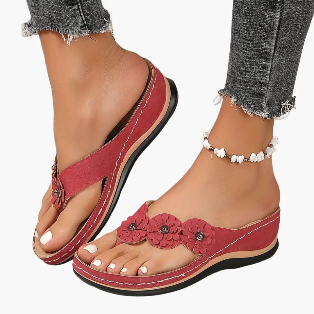 Pair of women's orthopedic red sandals with cushioned insole and floral-embellished straps, slip-on