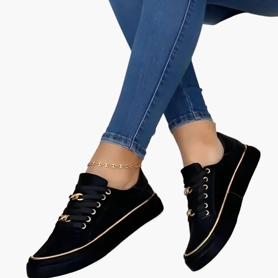 Pair of women's orthopedic sneakers, black with lace-up closure, cushioned sole, and gold-tone accents