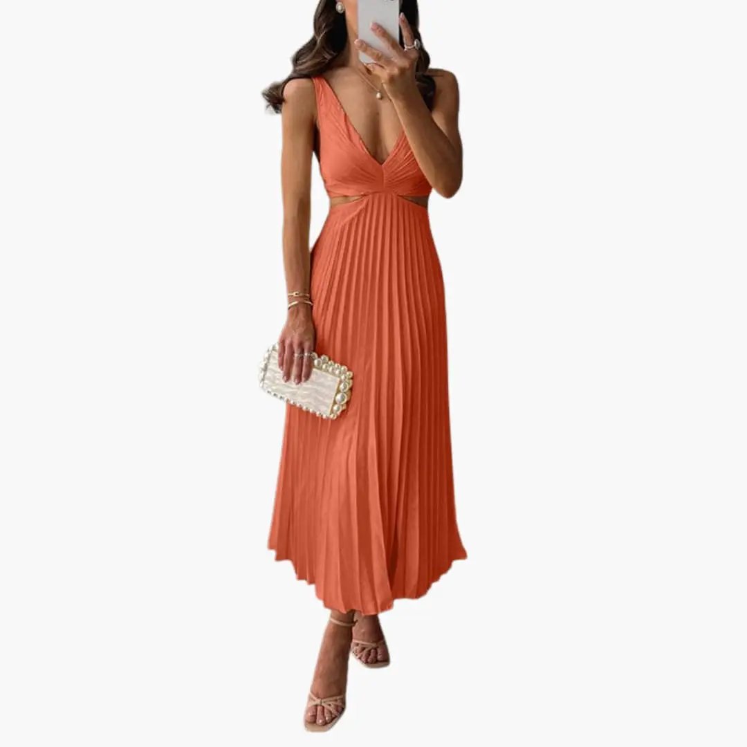 Women’s pleated satin dress in coral by Wilfred Smith with round neckline and flowing pleated skirt.