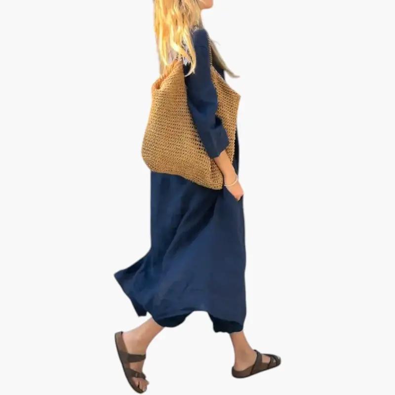 Two-piece women's navy blue outfit with short sleeves and full-length pants, model carrying a woven straw bag.